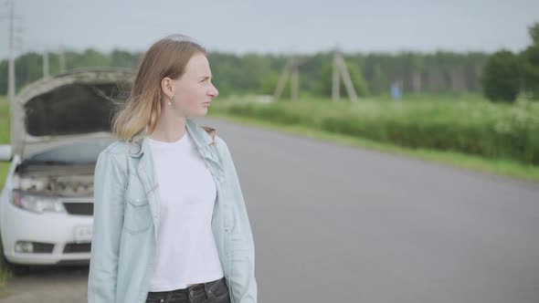 Young Woman Has a Broken Car and She Catches a Passing Car