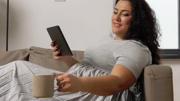 Woman with Tablet Pc Drinking Coffee at Home