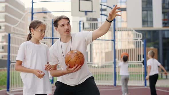 Handsome Male Coach Explaining the Throwing Technique of Basketball Game