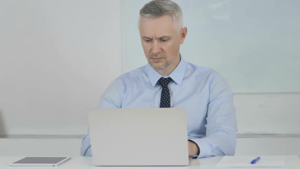 Senior Businessman Working on Laptop in Office