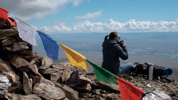 Female Traveler Drinking Tea on a Top of Mountain