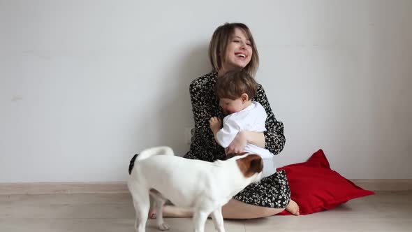 Little boy with mother sits near plant in pot on floor