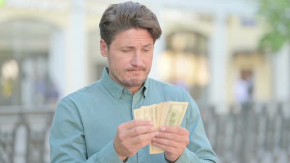 Portrait of Middle Aged Man Counting Dollars Outdoor