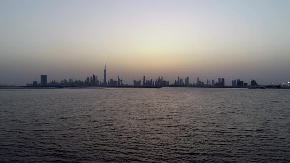 Aerial view at water level of Dubai skyscrapers and bay at sunset, UAE.