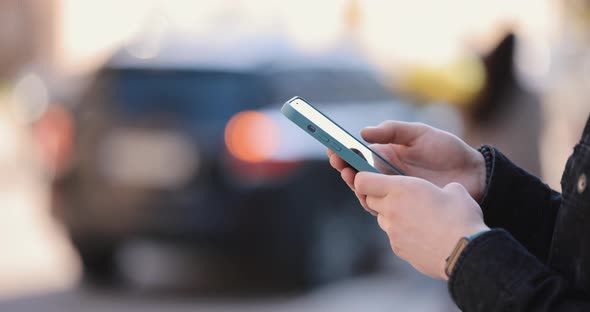 Closeup Male Hand Holding Smartphone in a City