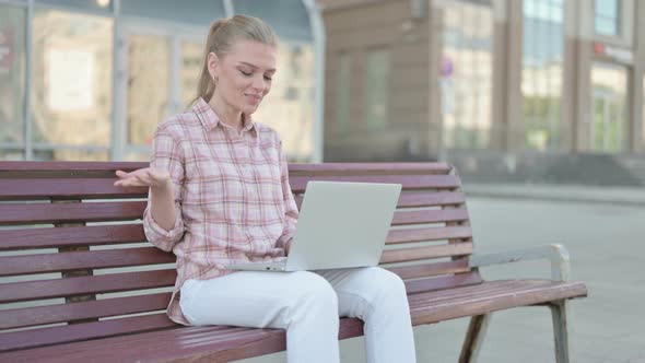 Young Woman Talking on Video Call While Sitting Outdoor on Bench