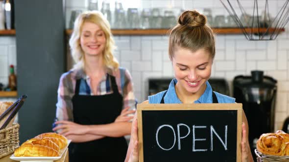Portrait of waitress standing with open sign board