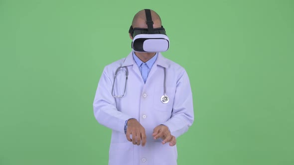 Handsome Bald Multi Ethnic Man Doctor Using Virtual Reality Headset