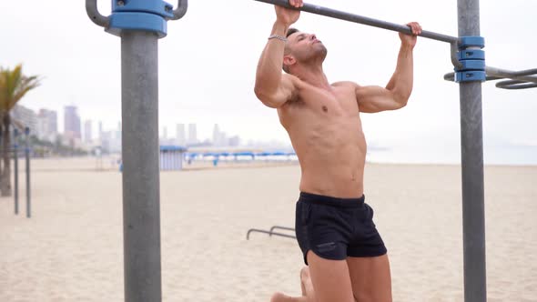 Fit sportsman doing pull ups on bar