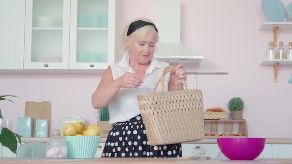 Stylish Senior Caucasian Woman Entering Kitchen with Buyings. Portrait of Confident Beautiful Mature