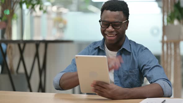 Video Call on Tablet By Young African Man in Modern Office