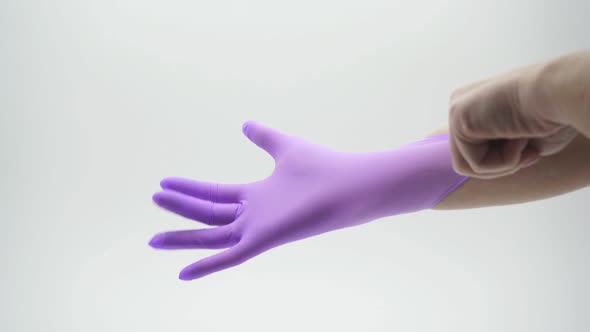 Close-up of a Woman's Hand Dressing a Medical, Latex, Nitrile, Lilac Glove on a White Background