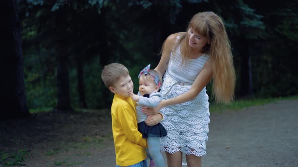 Young Mother and Her Two Sons Play with the Baby