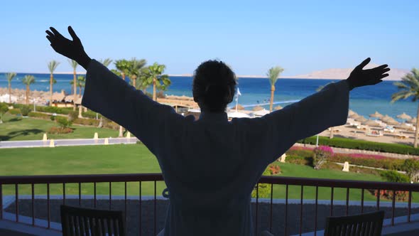 Woman Raising Arms On Balcony With Sea View On Vacation