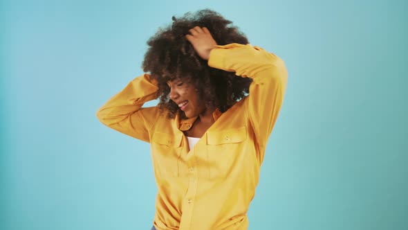 Ethnic Black Woman is Smiling Dancing and Having Fun While Posing Against Blue Studio Background