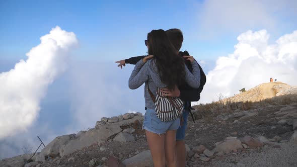 Young Couple of Tourists Standing at the Top of Mountain and Looking at Beautiful Landscape Forward