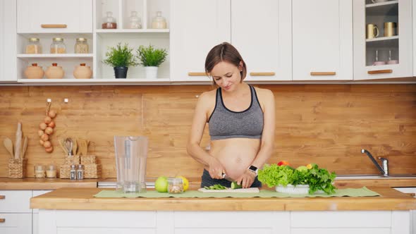 Pregnant Woman Preparing Fresh Green Salad On Kitchen