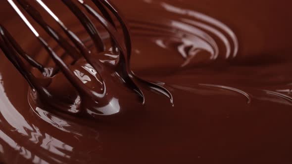 Melted chocolate close up. Stirring melted liquid chocolate with steel whisk. 4K UHD footage