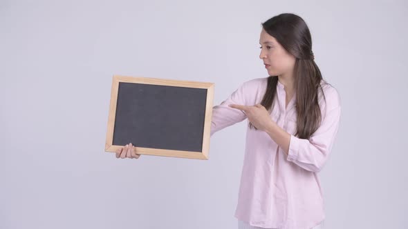 Young Multi-ethnic Businesswoman Holding Blackboard and Giving Thumbs Down