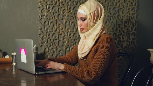 Young Muslim Woman Working on Business with Laptop in Cafe