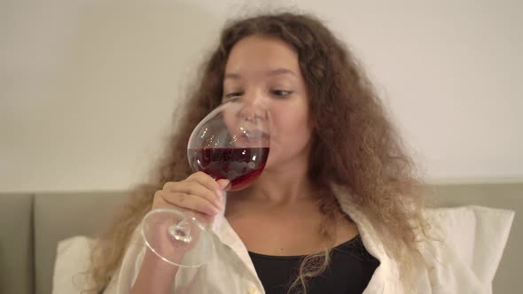 Peaceful Young Woman Drinks Red Wine From Large Wineglass