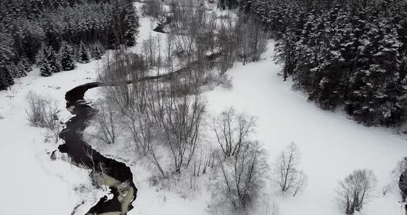 Flying Over Black River and Snow Covered Forest