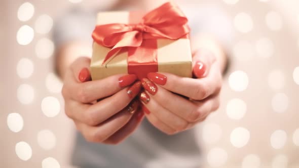 Woman Gives a Gift Box with Red Ribbon