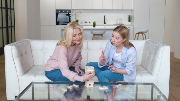 Grownup Daughter and Her Senior Mother Playing Board Game Enjoying Leisure Activity