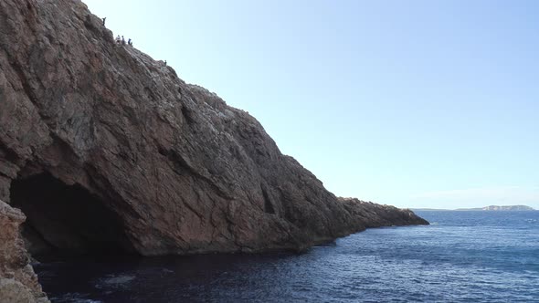 Large rocky cave in a cliff by the ocean. Stunning sea cave in Ibiza.