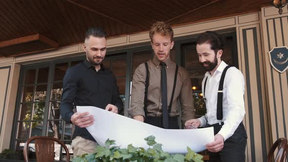 Serious Business Man Working with a Big Piece of Paper in Outdoor Cafe