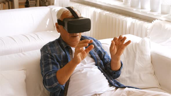Senior man using virtual reality headset in living room