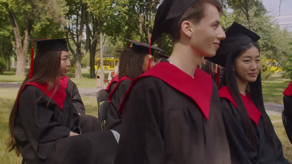 Lovely Black Student Whispering Gossip to Female Dean at Graduation Day