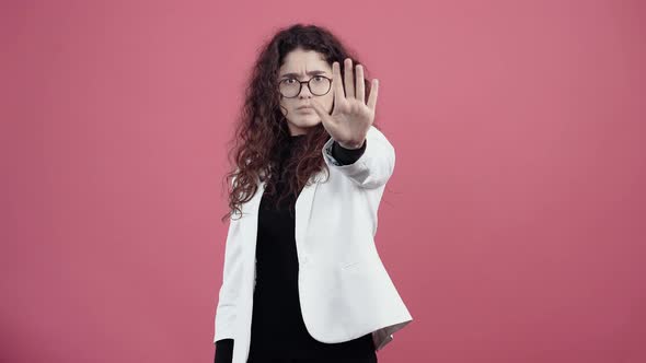 The Vigilant Young Woman with Curly Hair Stretches Out Her Hand in Front to Show the Stop Gesture