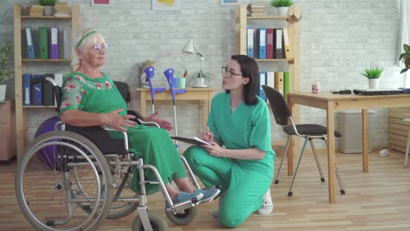 Doctor Checks the Health of an Elderly Woman in a Wheelchair