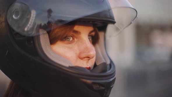 Portrait of Beautiful Young Redhaired Woman Motorcyclist in Helmet at Sunset