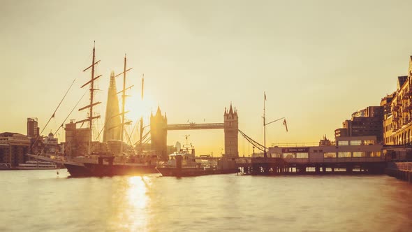 Time-lapse of the sun setting behind Tower Bridge, London, UK. A Tall ship is moored in the foregrou