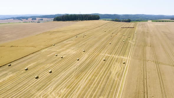 Aerial Drone Shot  Brown Field with Hay Bales in a Rural Area on a Sunny Day  Drone Flies Forward