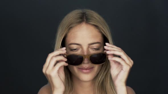 Young woman putting on fashionable sunglasses