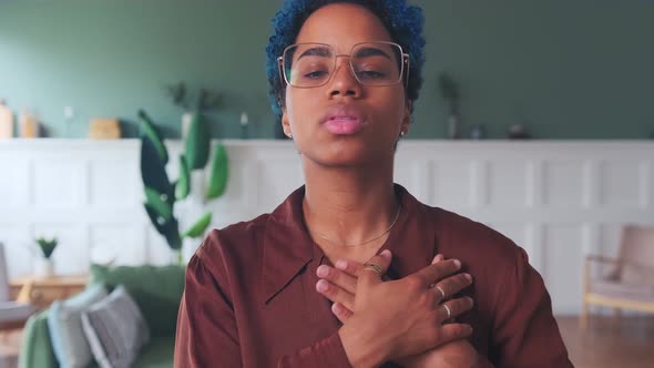 Young Serious African American Woman Puts Hands on Heart As Token of Gratitude