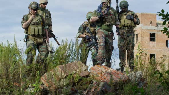 Military Men Posing with Weapons Outdoors