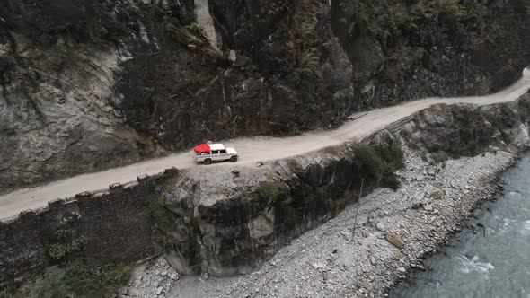 Panning view of vehicle driving on road next to the Marsyangdi River