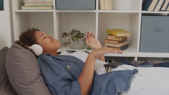 Female Student Listening to Music in Bed