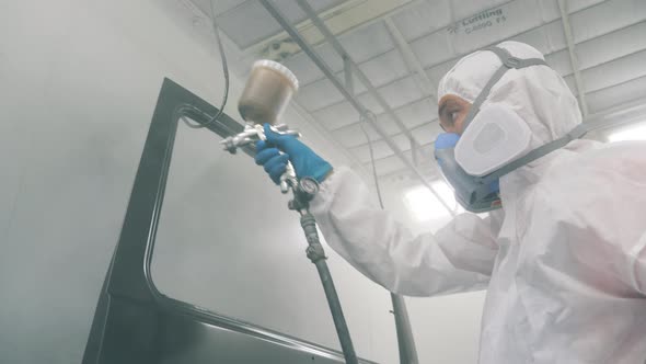 Serviceman Is Using the Painting Nozzle To Colour the Car. Industrial Spray Painting Process.