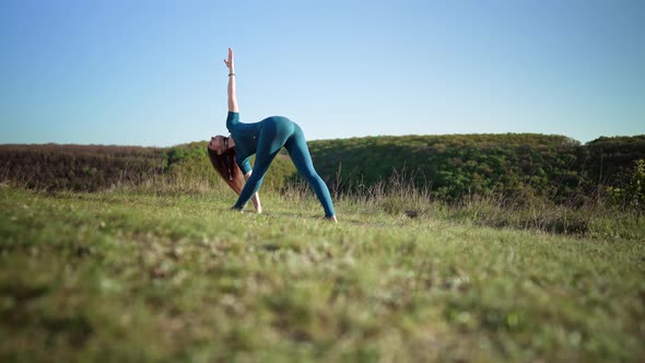 Yogi Woman on Top of High Mountain Doing Yoga Practice  Parivrtta Trikonasana with Deep Breathing