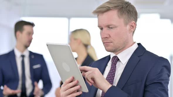 Portrait of Focused Businessman Using Tablet in Office