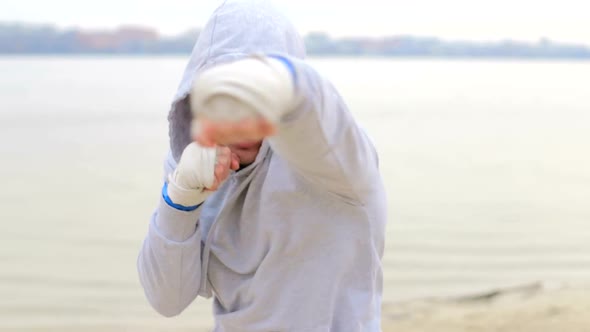 Boxing a man with an invisible opponent. A young man trains outdoors.