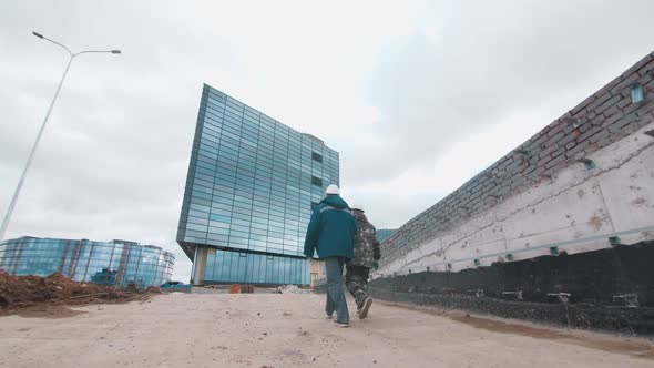 Workers Walk Along Construction Site to High Rise Buildings alt