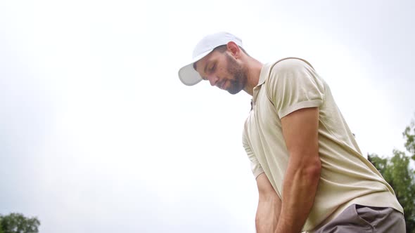 Young golfer in a cap hitting a golf ball with a golf club