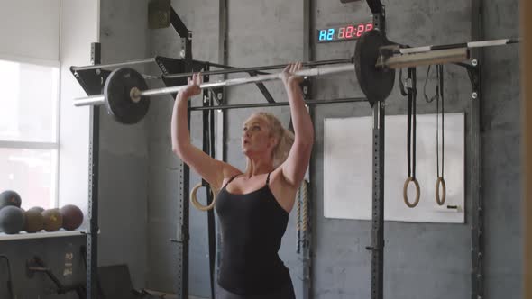Woman Doing Barbell Overhead Squats in Gym alt