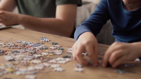 Video of boredom boy solving jigsaw puzzle during father working. Shot with RED helium camera in 8K.